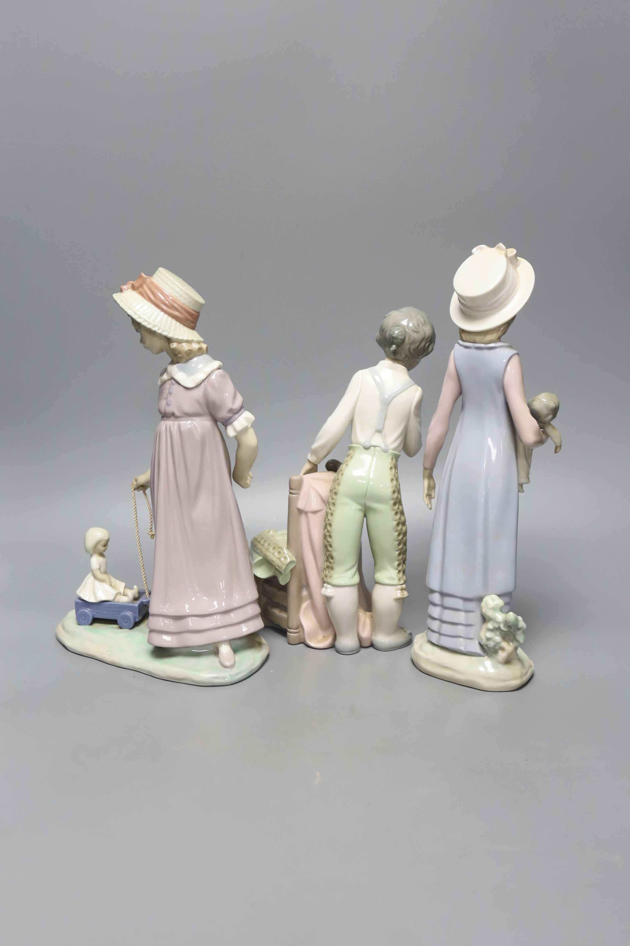 A Lladro figure of a girl with a doll, another girl with a doll in a toy cart and a matador, tallest 28cm